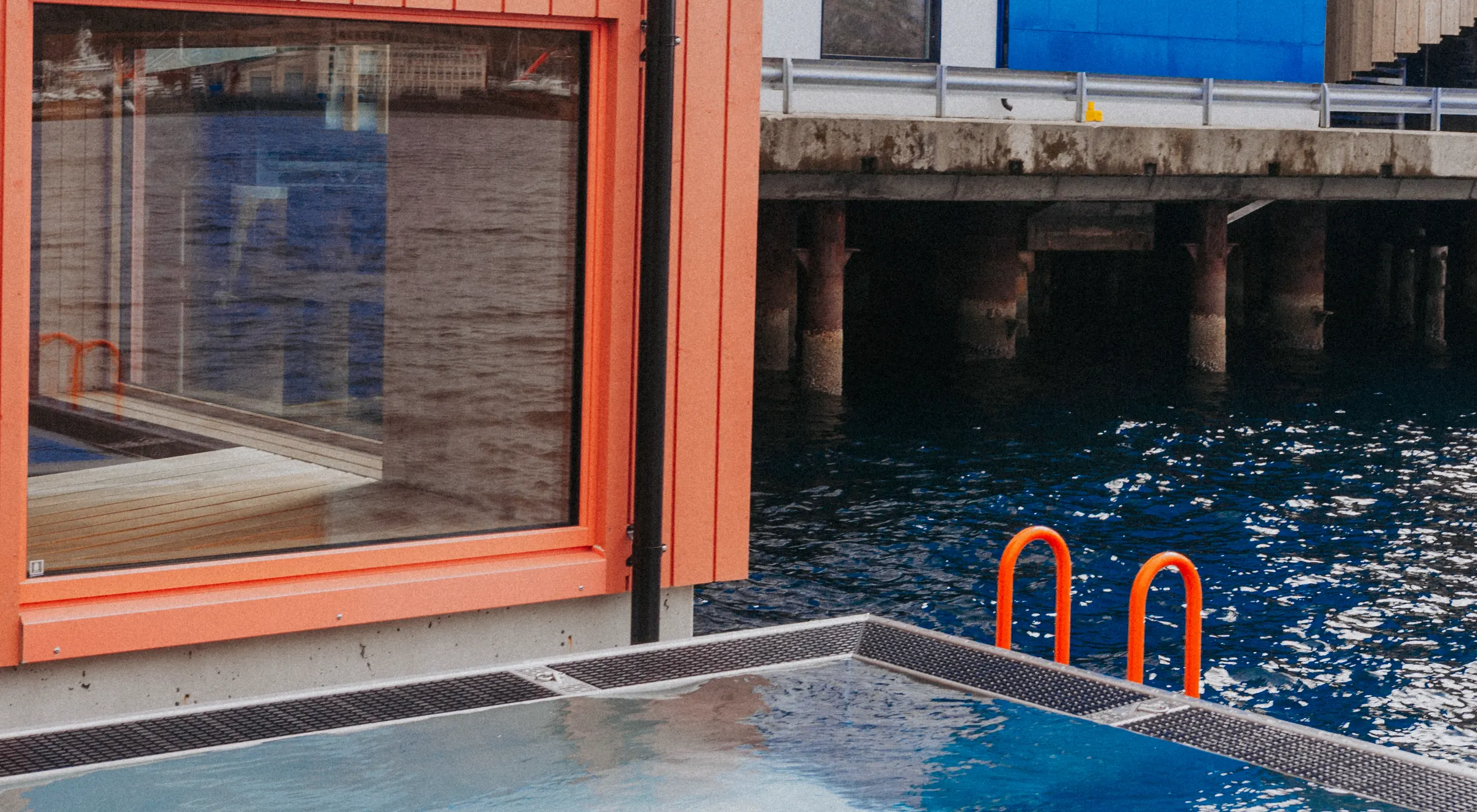 Floating sauna with an orange facade beside a harbour pool