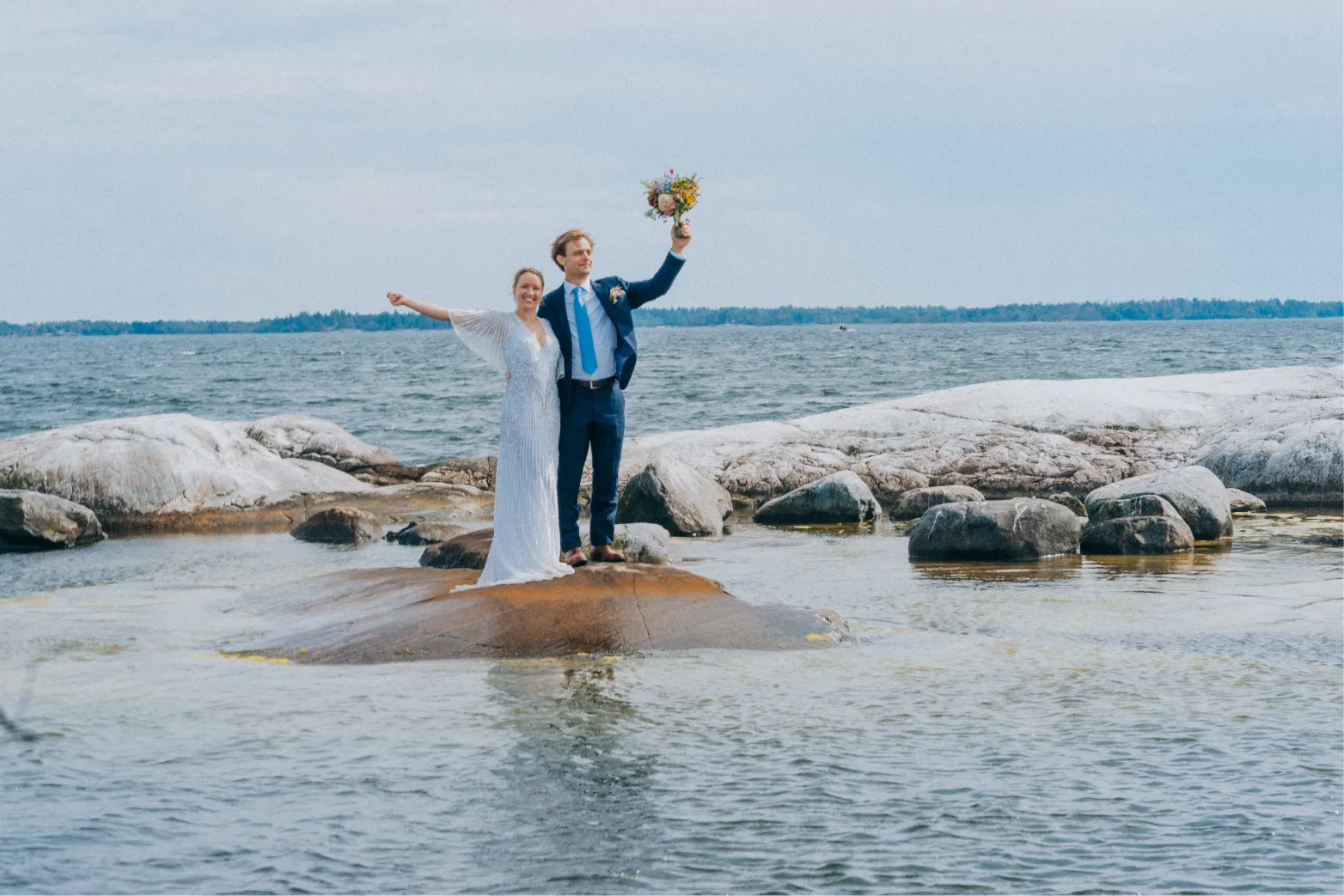 Karin and Uno waving from a rock in the archipelago